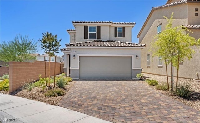 view of front of house featuring fence, a tile roof, decorative driveway, an attached garage, and stucco siding