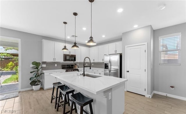 kitchen featuring a sink, decorative backsplash, stove, baseboards, and stainless steel fridge with ice dispenser
