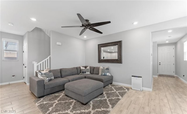 living room with a healthy amount of sunlight, a ceiling fan, light wood-style flooring, and baseboards