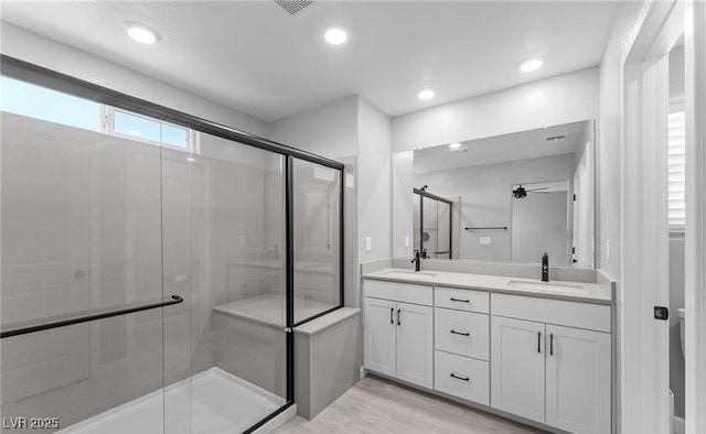 full bath featuring double vanity, a shower stall, recessed lighting, and a sink