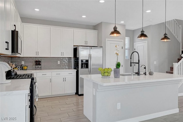 8349 Pollenzo Ave, Las Vegas, NV 89178 - kitchen featuring appliances with stainless steel finishes, a sink, white cabinetry, decorative backsplash, and a kitchen island with sink