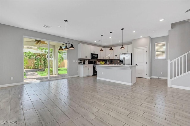 8349 Pollenzo Ave, Las Vegas, NV 89178 - kitchen featuring range with electric stovetop, stainless steel fridge with ice dispenser, black microwave, open floor plan, and plenty of natural light