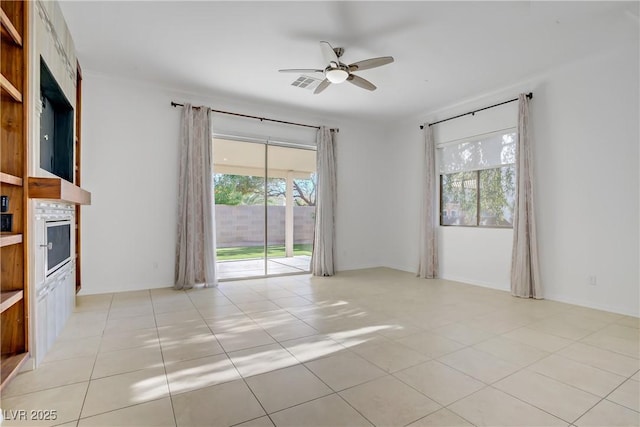 437 Via Stretto Ave, Henderson, NV 89011 - unfurnished room featuring a fireplace, a ceiling fan, visible vents, and a wealth of natural light