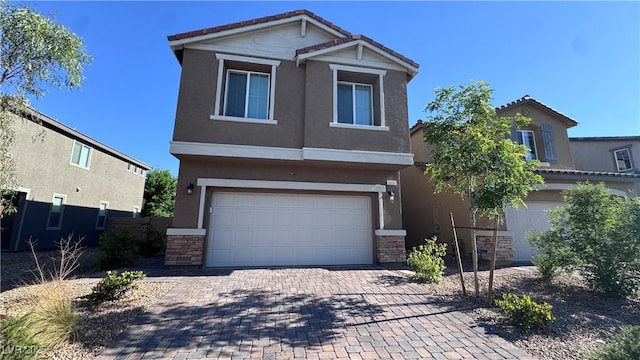 view of front of home with an attached garage, stucco siding, stone siding, and decorative driveway