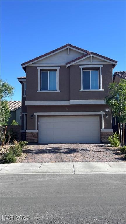 view of front facade featuring stucco siding, decorative driveway, and a garage