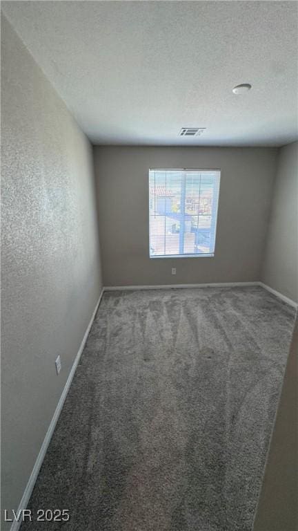 carpeted spare room with baseboards and a textured ceiling