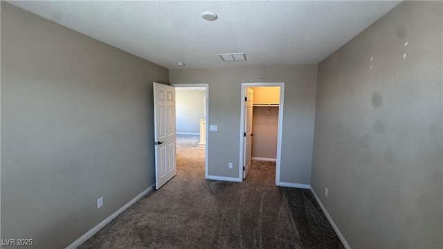 unfurnished bedroom featuring carpet floors, a spacious closet, baseboards, and a closet
