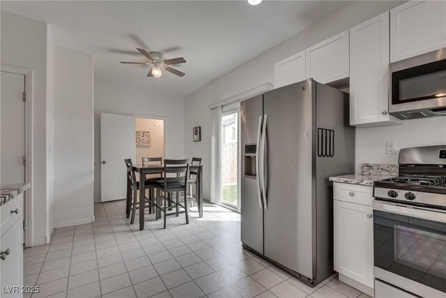 5256 Sherwood Forest Ln, Las Vegas, NV 89122 - kitchen featuring light tile patterned floors, white cabinetry, a ceiling fan, light stone counters, and stainless steel appliances