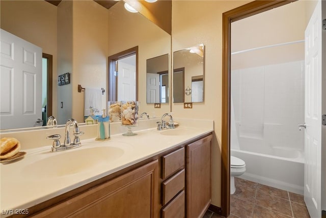 bathroom featuring toilet, double vanity, a sink, and tile patterned flooring