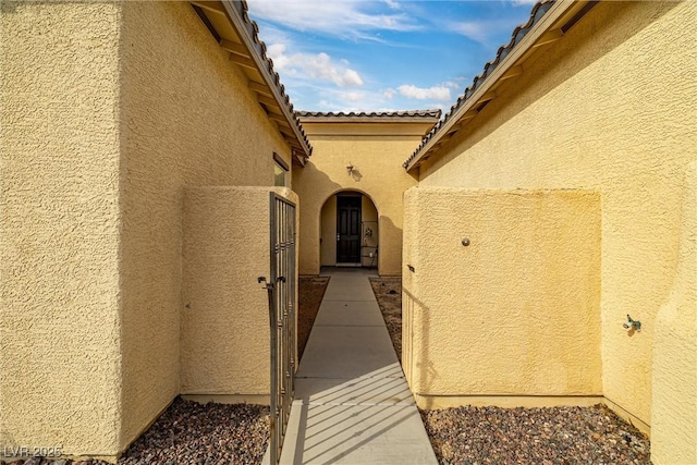 doorway to property featuring stucco siding and a tiled roof