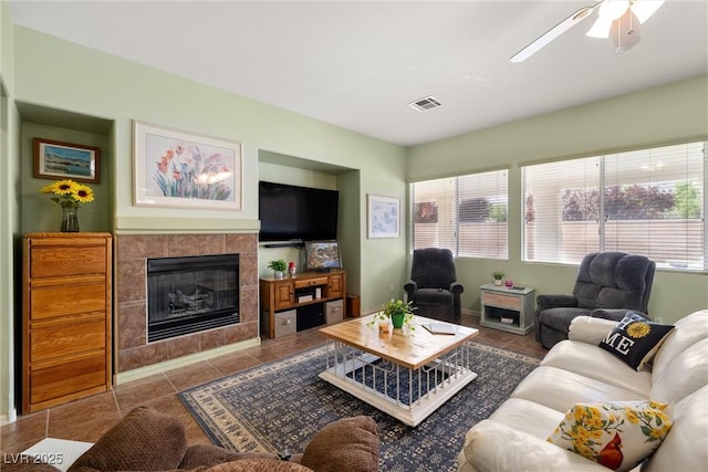 living area with tile patterned flooring, a tile fireplace, visible vents, and a ceiling fan