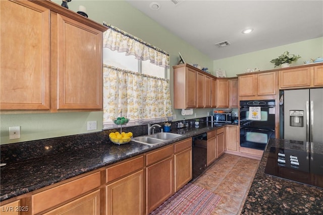 kitchen with dark stone countertops, light tile patterned floors, black appliances, visible vents, and a sink