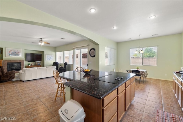 kitchen with tile patterned floors, arched walkways, plenty of natural light, and black electric stovetop
