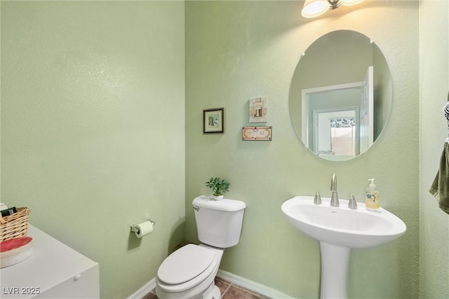 half bathroom featuring toilet, tile patterned floors, and baseboards