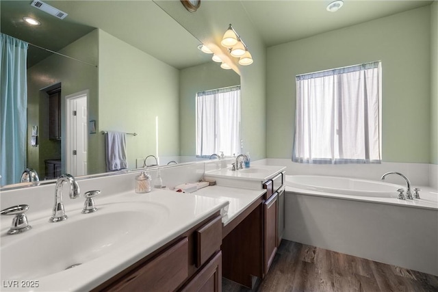 full bathroom featuring a bath, wood finished floors, vanity, and visible vents
