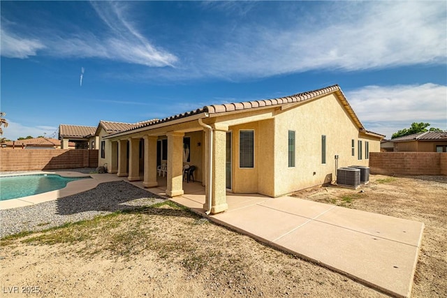 rear view of house featuring a patio, a fenced backyard, a fenced in pool, and a tile roof