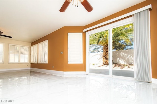 spare room with marble finish floor, ceiling fan, and baseboards