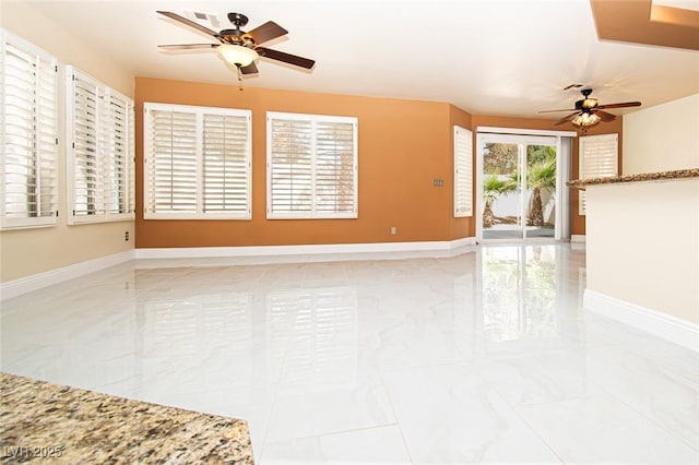 spare room featuring ceiling fan, marble finish floor, and baseboards