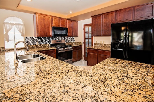 kitchen with black appliances, recessed lighting, light stone counters, a sink, and backsplash