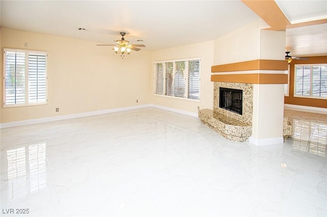 unfurnished living room featuring baseboards, a ceiling fan, marble finish floor, and a high end fireplace