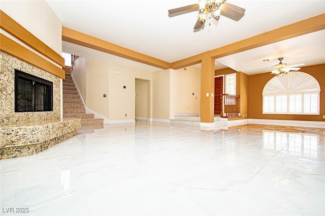 unfurnished living room featuring marble finish floor, ceiling fan, baseboards, and stairs