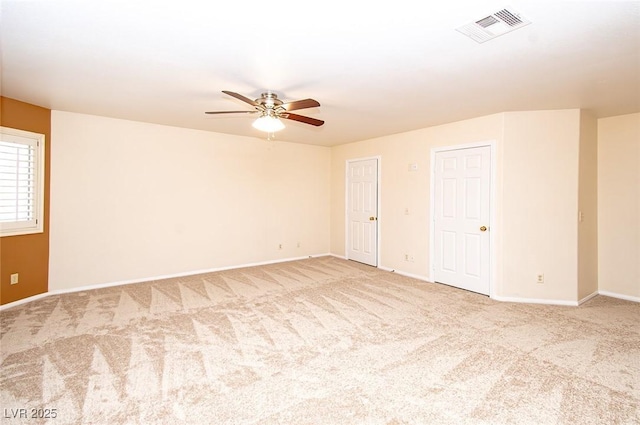 carpeted spare room featuring baseboards, a ceiling fan, and visible vents