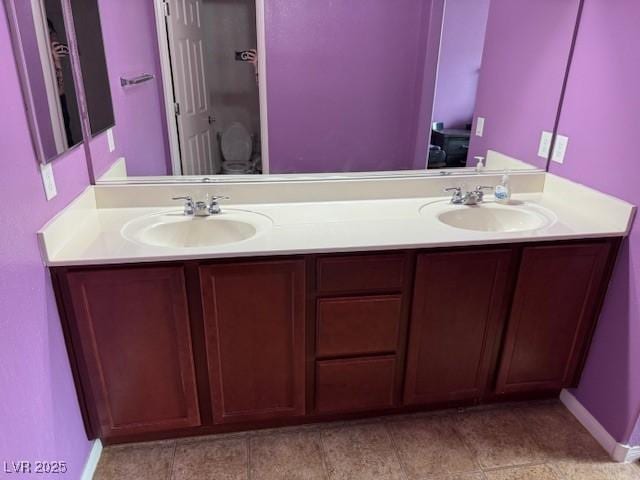 full bathroom featuring a sink, baseboards, and double vanity