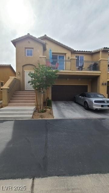 view of front of house with concrete driveway, a balcony, stucco siding, and an attached garage