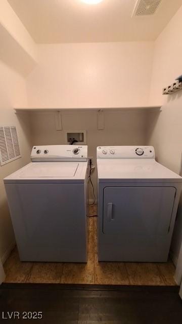 clothes washing area featuring visible vents, washer and clothes dryer, and laundry area