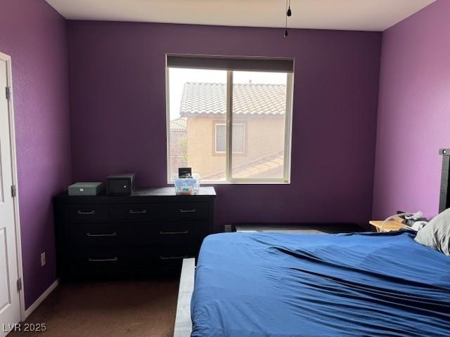 bedroom featuring dark colored carpet and baseboards