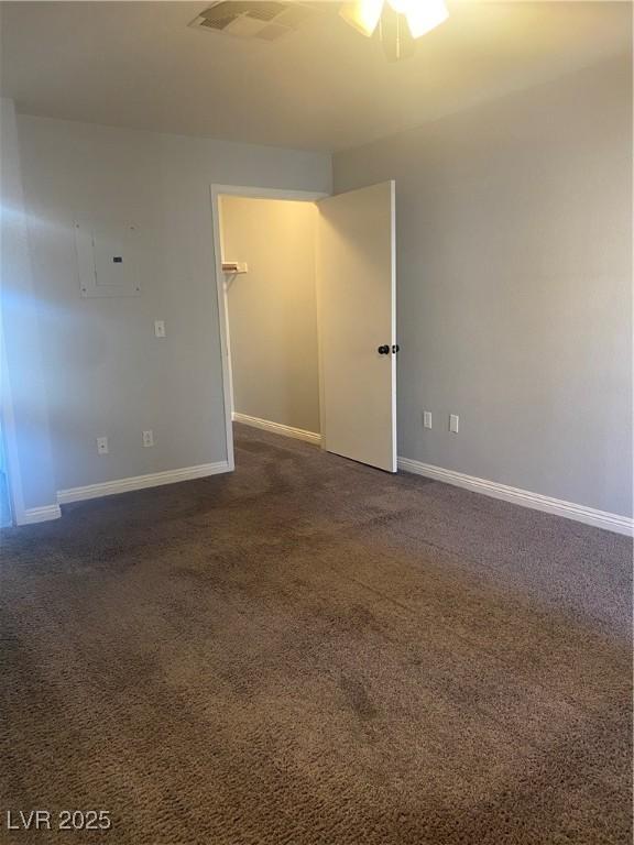 spare room with dark colored carpet, visible vents, and baseboards