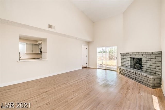 4488 Los Reyes Ct, Las Vegas, NV 89121 - unfurnished living room featuring light wood-style floors, high vaulted ceiling, a fireplace, visible vents, and baseboards