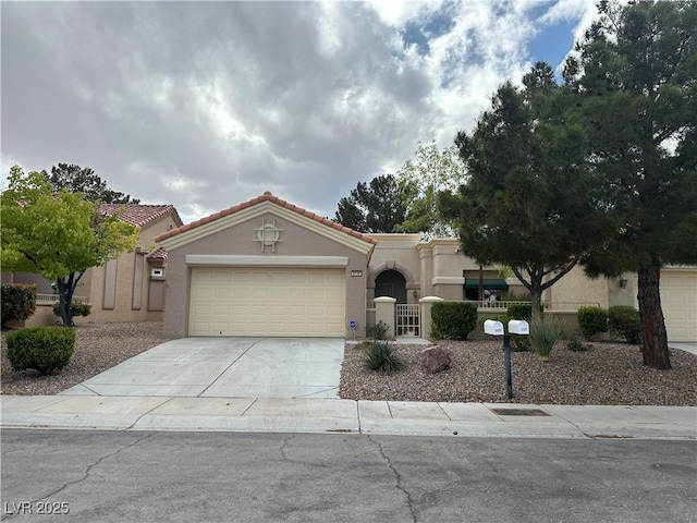 mediterranean / spanish home featuring concrete driveway, stucco siding, a tiled roof, and an attached garage