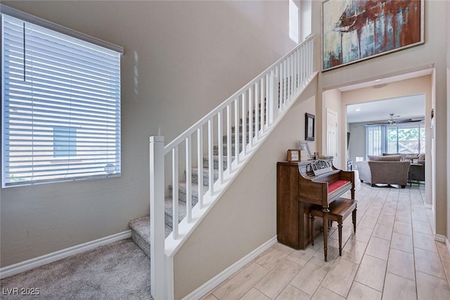 staircase with a ceiling fan and baseboards