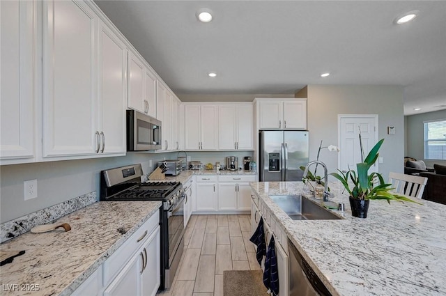 kitchen featuring white cabinets, a sink, recessed lighting, light stone countertops, and appliances with stainless steel finishes