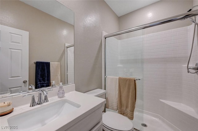 bathroom featuring a shower stall, toilet, and vanity