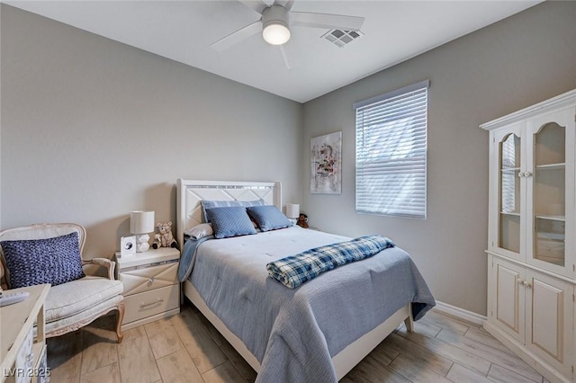 bedroom with baseboards, a ceiling fan, visible vents, and wood finish floors