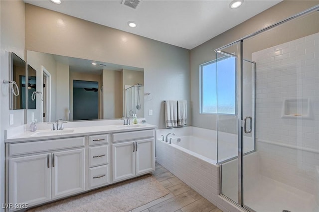 full bathroom with double vanity, visible vents, a sink, a garden tub, and a stall shower