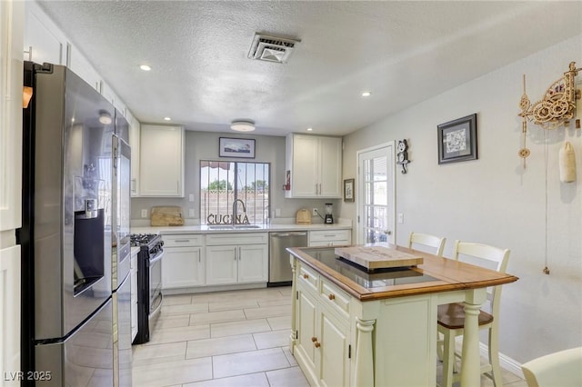 kitchen featuring white cabinets, stainless steel appliances, visible vents, and a sink