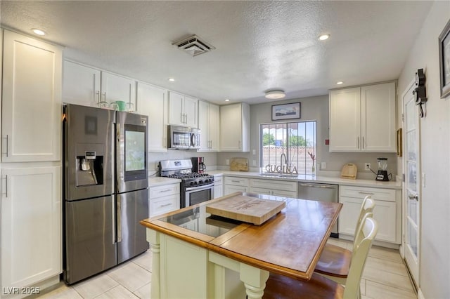 kitchen featuring white cabinets, recessed lighting, stainless steel appliances, visible vents, and a sink