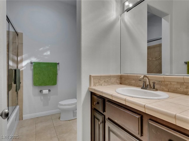 full bath with shower / bath combination with glass door, tile patterned flooring, toilet, vanity, and baseboards