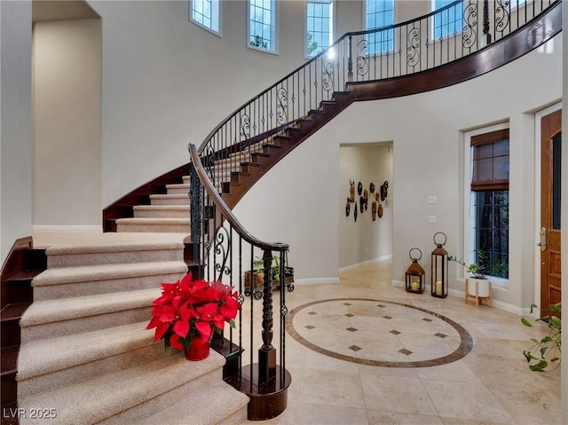 stairs featuring baseboards, a high ceiling, and tile patterned flooring
