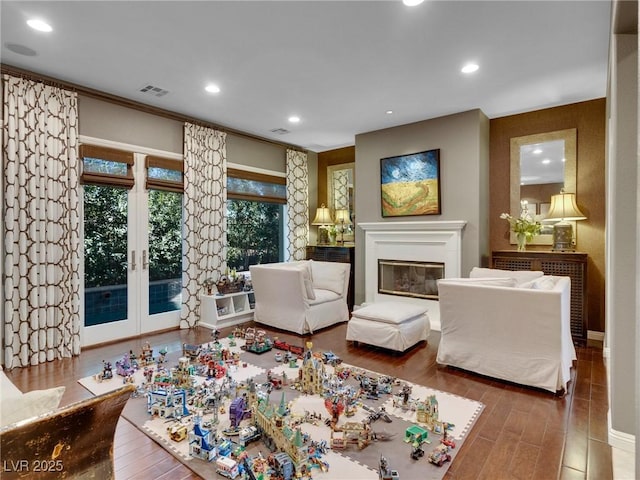 living room featuring french doors, visible vents, a glass covered fireplace, recessed lighting, and wood finished floors