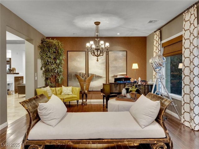 living area featuring a chandelier, wood-type flooring, visible vents, and baseboards