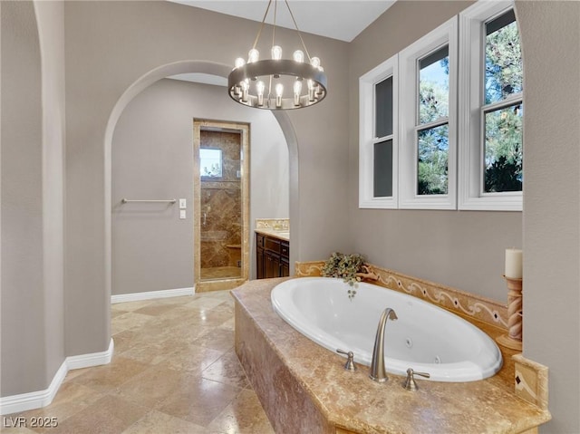 full bathroom featuring a tub with jets, a stall shower, vanity, baseboards, and a notable chandelier
