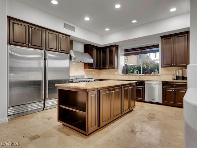 kitchen with decorative backsplash, wall chimney exhaust hood, stainless steel appliances, and a kitchen island