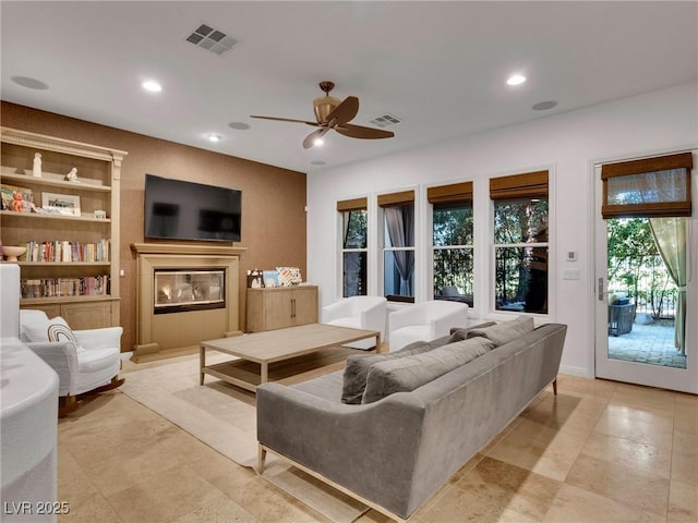 living room featuring recessed lighting, a glass covered fireplace, visible vents, and ceiling fan