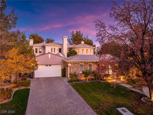 view of front of property featuring a chimney, a front lawn, driveway, a garage, and stucco siding