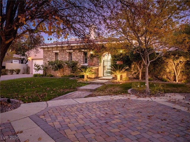 single story home with stone siding, concrete driveway, a garage, a front yard, and stucco siding