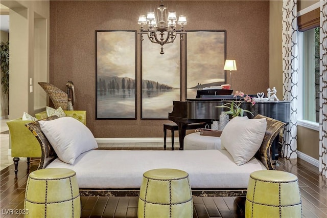 living area with baseboards, a chandelier, and wood finished floors